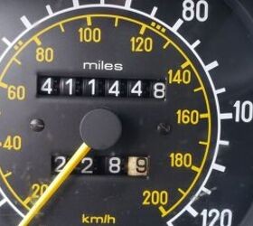 Front quarter view of a 1985 Mercedes Benz 300D Turbo Diesel in a junkyard, highlighting its high mileage odometer reading of 411,448 miles