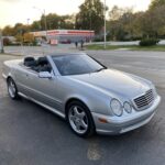 Front quarter view of a silver 2000 Mercedes CLK 430 convertible parked outdoors, showcasing its elegant design and AMG styling elements.