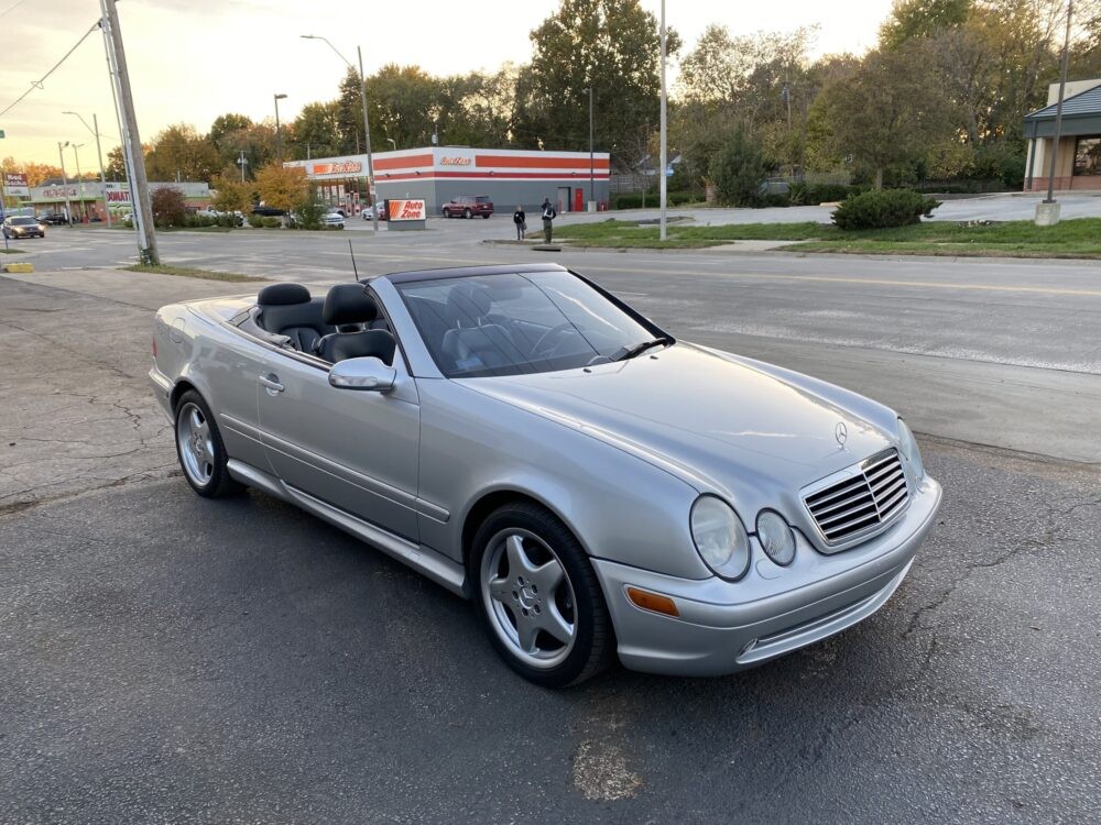 Front quarter view of a silver 2000 Mercedes CLK 430 convertible parked outdoors, showcasing its elegant design and AMG styling elements.