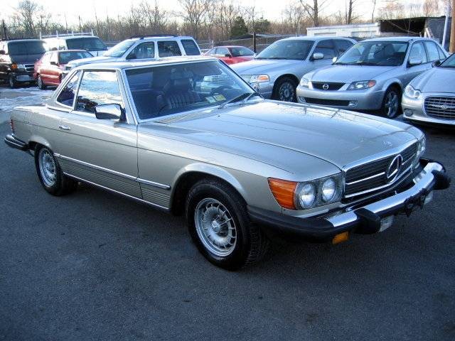 Front three quarter view of a red 1985 Mercedes-Benz 380SL parked outdoors.