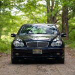 Front view of a silver Mercedes-Benz C32 AMG parked outside on a sunny day.