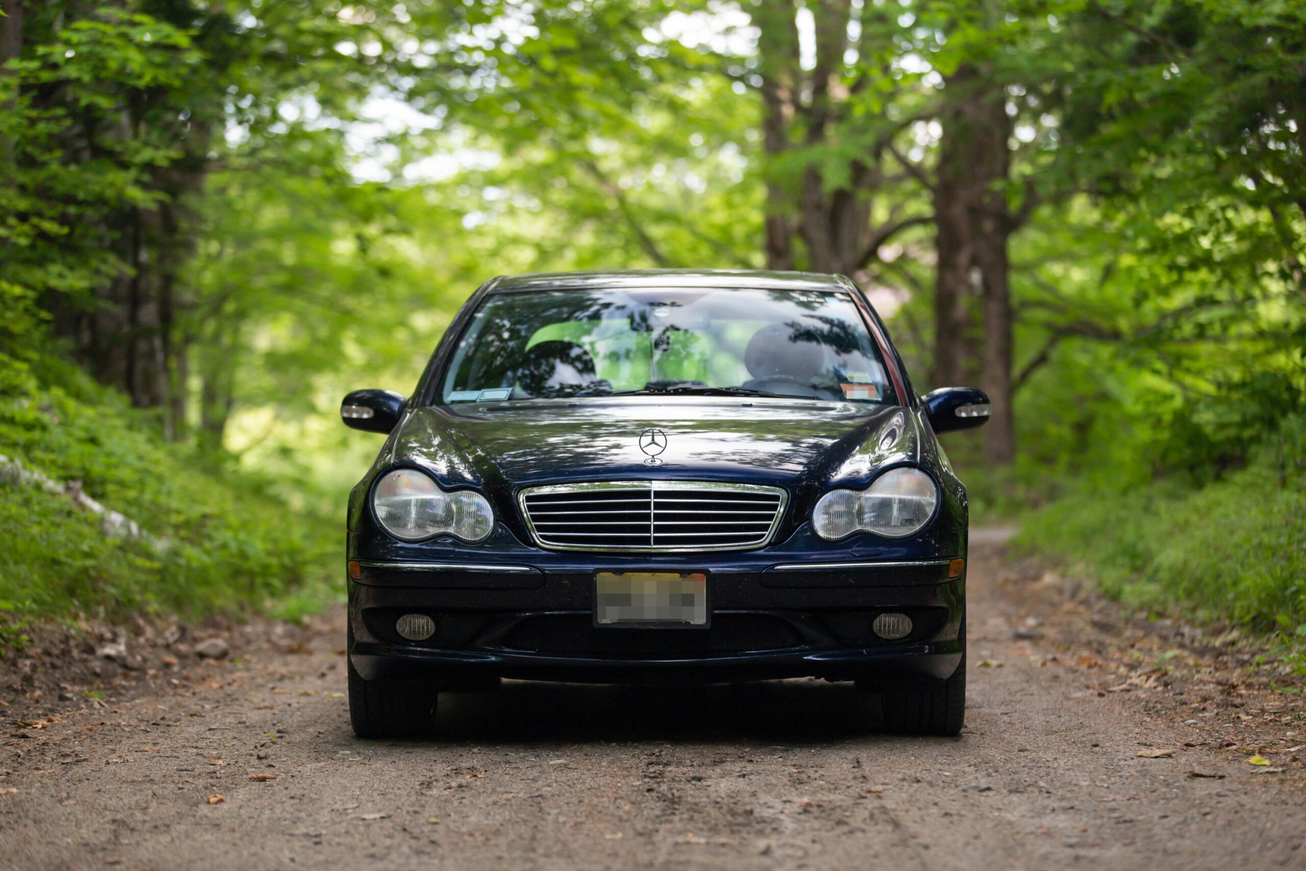 Front view of a silver Mercedes-Benz C32 AMG parked outside on a sunny day.