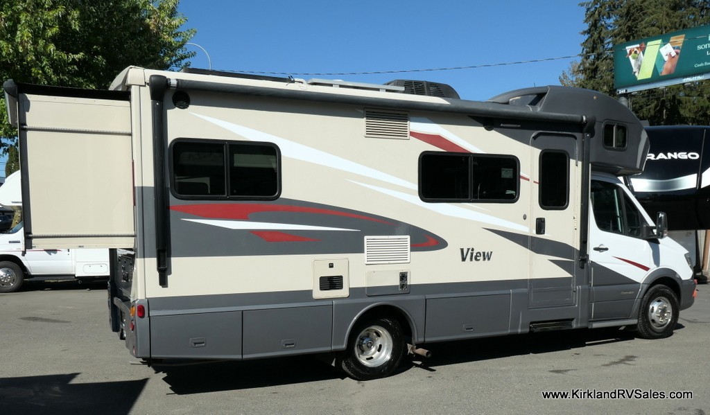 Interior living area of the RV with slide-out extended showing dinette and overhead cabinets.