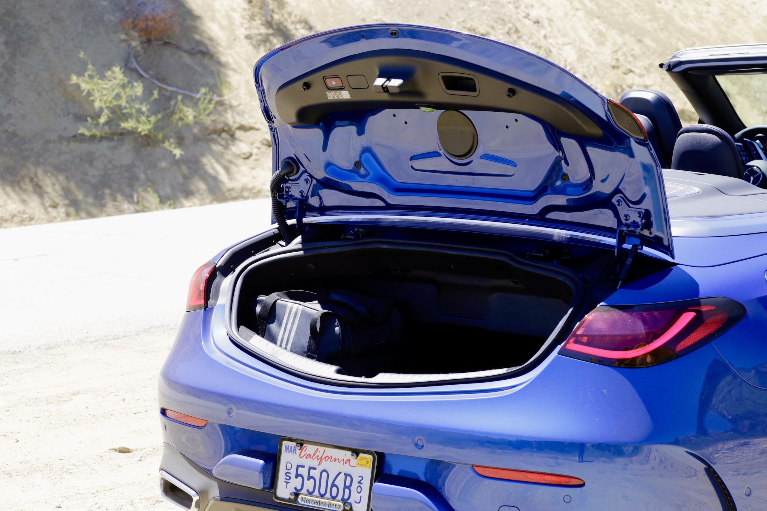 Side view of the 2024 Mercedes-Benz CLE300 Cabriolet parked on a scenic road, emphasizing its grand touring character.